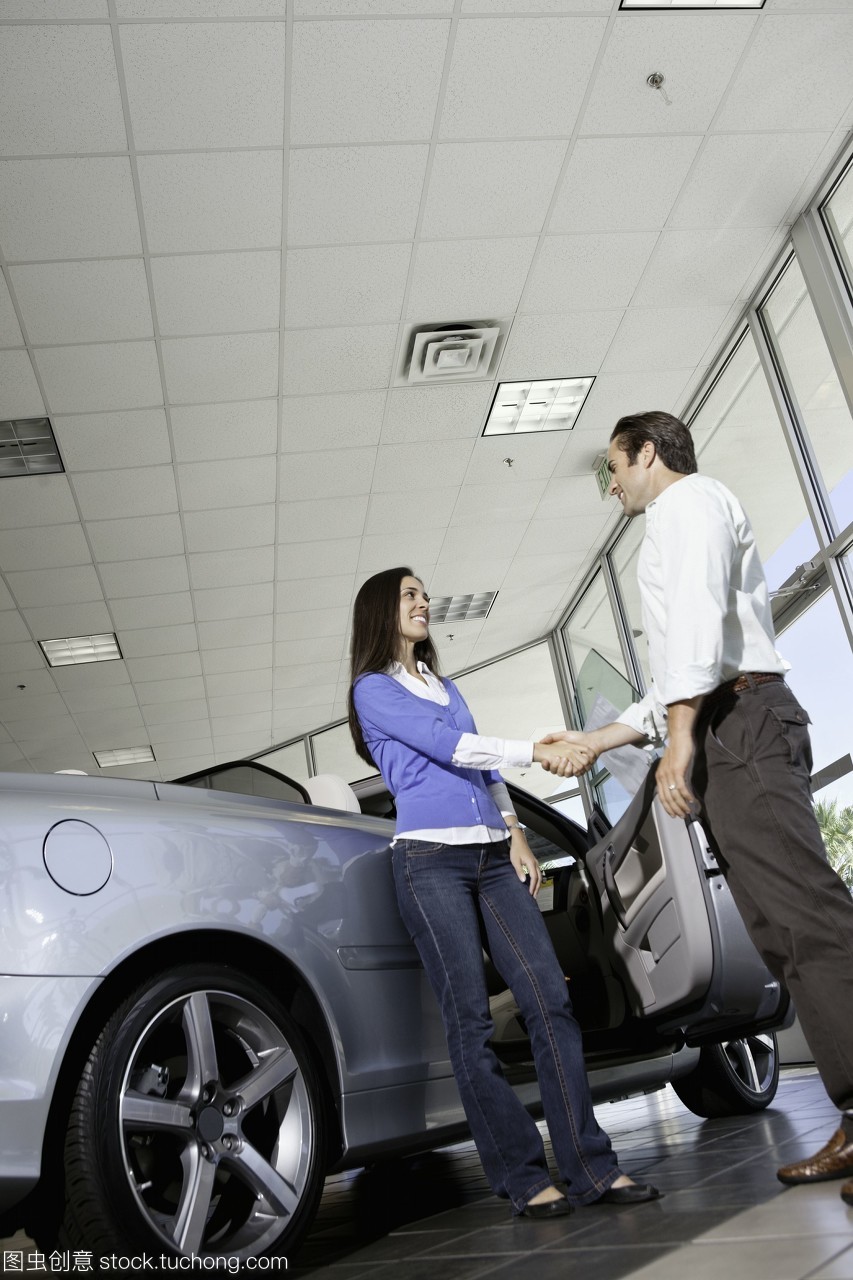 汽车销售员在展示室与女顾客握手